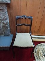 Front view of carved wood side chair beside stone fireplace