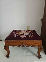 Front view of ottoman showing carved legs and apron