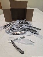 Open box showing multiple packaged folding razors, one razor displayed outside sleeve