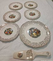 All seven porcelain pieces laid out: six plates, one pie server