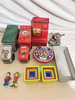 All items in lot: two tin trucks, red coin bank, wind-up UFO, two action figures, two nesting block sets, small Yoda figurine