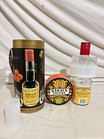 Bottle, tin, plastic holder, lid displayed