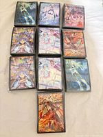 Nine anime illustrated sleeve packs and one plain black pack arranged in rows