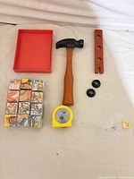 All items laid out: measuring tape, hammer, plank, nuts, tray, puzzle cubes