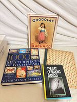 Front view showing all items: three hardcover books and mounted Chocolat Suchard print
