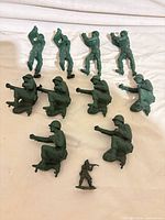 Group shot of all 11 green plastic toy soldiers laid out