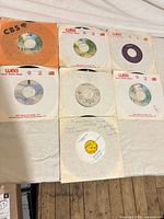 Seven 7" singles in assorted company sleeves on table