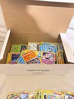 Open cardboard box filled with stacked Pokémon cards