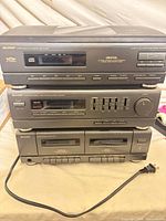 Front view of stacked Sharp receiver, CD changer, cassette deck with power cord