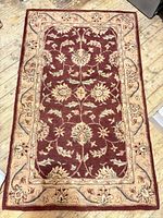 Full view of burgundy and beige Oriental rug on wood floor