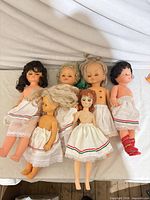Six hard plastic dolls laid on sheet