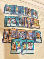 Wide shot of three grouped stacks of Yu-Gi-Oh! cards showing mix of types