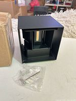 Front view of cube light beside box with mounting hardware in bag