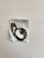 Sealed black charging cable in clear plastic bag front view