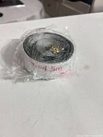 sealed roll of black foam weatherstripping with brass screws seen through plastic