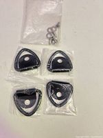 Four sealed black metal strap locks and separate bag of screws and washers