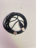 Coiled black USB-A to USB-A cable showing both connectors
