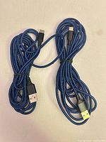 Two coiled blue braided USB-A to USB-C cables with connectors visible