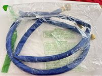 Coiled blue hose with brass connectors in sealed plastic