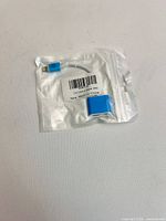 Front view of sealed polybag showing blue adapter cable and barcode label