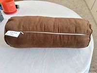 Side view of brown cylindrical pillow showing zipper and overall shape