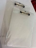 Two clear acrylic clipboards in plastic wrap, front view
