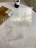 Two clear acrylic photo frames with scalloped borders and easel backs
