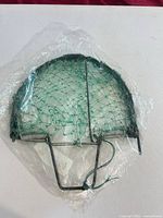 Hoop net trap in unopened plastic wrap, showing metal frame, springs and green mesh