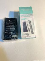 Charger sealed in plastic next to original box front; label text and barcode visible