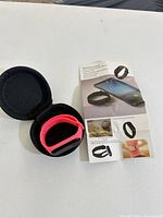 Tracker in pink band inside black zippered case with leaflet beside
