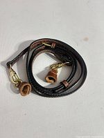 Coiled brown leather strap showing gold-tone clasps and rolled leather protectors