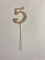 Front view of gold rhinestone number 5 cake topper with pick
