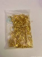 Sealed plastic bag filled with numerous gold plated keychain hardware pieces