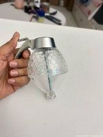 Side view of clear honeycomb-patterned mister showing trigger handle and internal spray tube