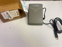 Top view of gray IRIS foot pedal with cord and box