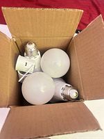 Top view of open box showing three frosted A19 LED bulbs with E26 bases inside