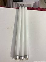 Three frosted fluorescent tubes laid side by side showing bi-pin ends
