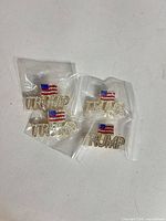 Four rhinestone TRUMP flag lapel pins in individual plastic bags