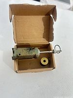 Open box showing main cylinder with rod, gold sleeve and cotter pin