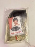 Front view of packaged nylon hair net with New Fashion branding