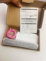 Open box showing shower arm extension wrapped, pink thread tape and instructions