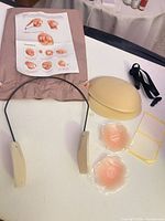 Entire kit laid out: wire frame, storage shell, nipple covers, adhesive pads, strap and instructions