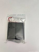 Front view of sealed package showing two black battery holders and label