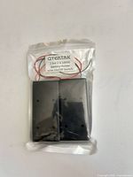 Front view of sealed package showing two black battery holders and label