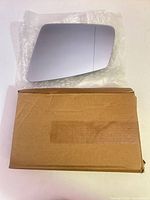 Front reflective surface of mirror glass resting on bubble wrap above cardboard box