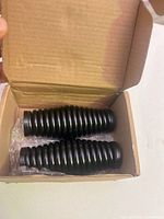 Pair of black rubber bellows in open box with bubble wrap