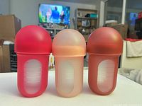 Front view of three silicone baby bottles showing colors and measurement windows