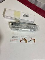 Handpiece wrapped in bubble wrap beside white box and instruction card