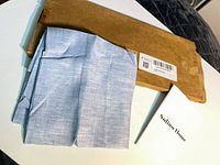 Folded light blue textile panel, cardboard mailing box, Solino Home booklet visible