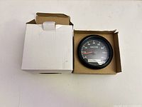 tachometer in open box front view showing scale and needle